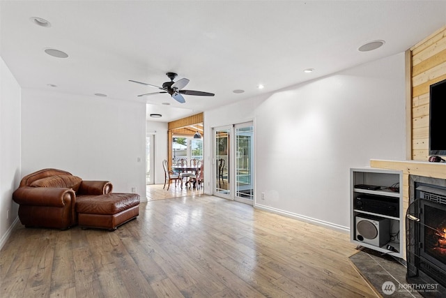 living area with baseboards, recessed lighting, a ceiling fan, a fireplace with flush hearth, and hardwood / wood-style floors