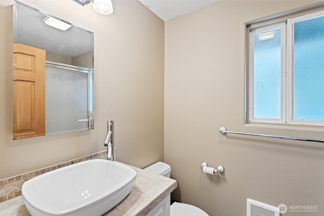 bathroom featuring visible vents, toilet, a stall shower, and vanity