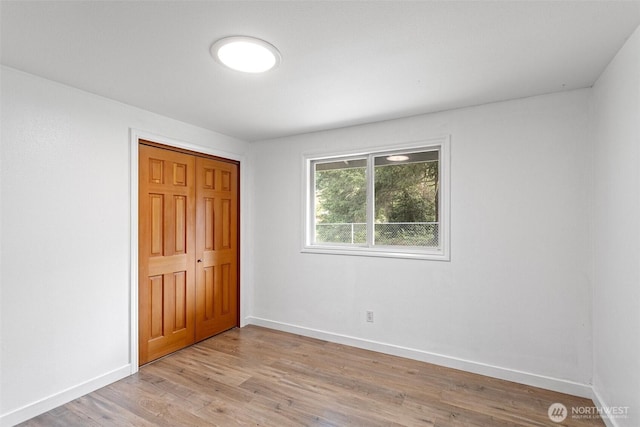 unfurnished bedroom with a closet, baseboards, and light wood-type flooring