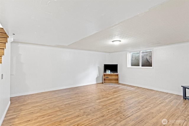 unfurnished living room with light wood-style floors, baseboards, and a textured ceiling