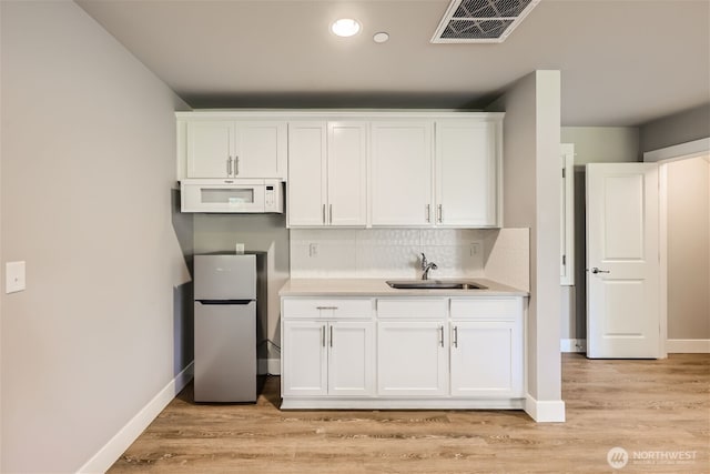 16216 81st Pl NE, Kenmore, WA 98028 - kitchen with freestanding refrigerator, white microwave, a sink, white cabinets, and recessed lighting