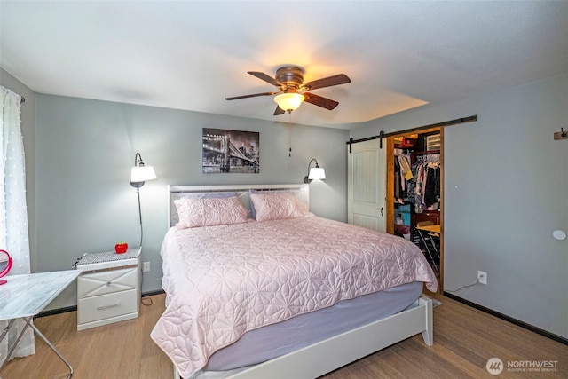 9365 Central Valley Rd NE, Bremerton, WA 98311 - bedroom with ceiling fan, a closet, a barn door, wood finished floors, and baseboards