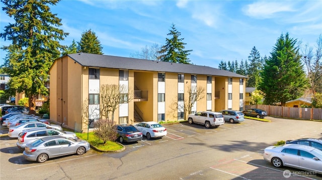 view of building exterior featuring fence and uncovered parking