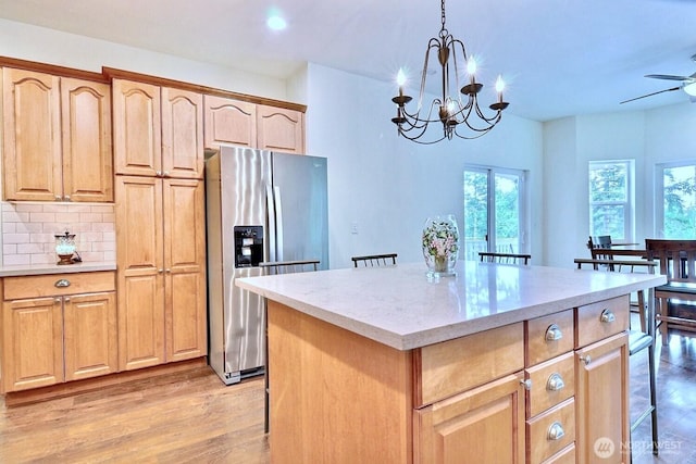 1921 NE Haven Way, Tahuya, WA 98588 - kitchen featuring light wood-style flooring, a kitchen island, stainless steel refrigerator with ice dispenser, decorative backsplash, and ceiling fan with notable chandelier