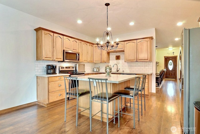 1921 NE Haven Way, Tahuya, WA 98588 - kitchen featuring light countertops, a kitchen island, a breakfast bar area, stainless steel appliances, and wood finished floors
