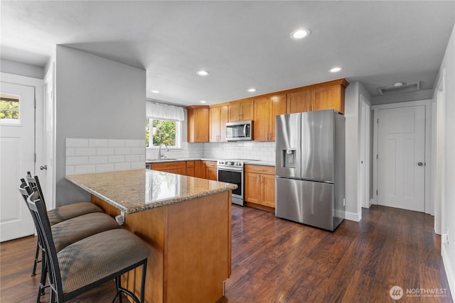 22115 103rd Pl SE, Kent, WA 98031 - kitchen with stainless steel appliances, a peninsula, light stone countertops, dark wood-style floors, and decorative backsplash