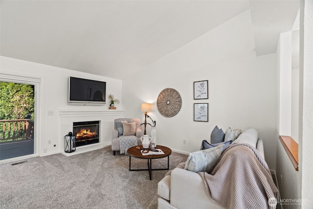 carpeted living room featuring visible vents, baseboards, vaulted ceiling, and a brick fireplace