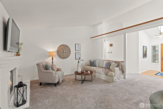 living room featuring baseboards, a fireplace, carpet, and vaulted ceiling