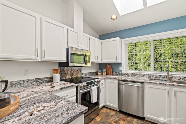 kitchen featuring a sink, appliances with stainless steel finishes, light stone counters, and white cabinetry