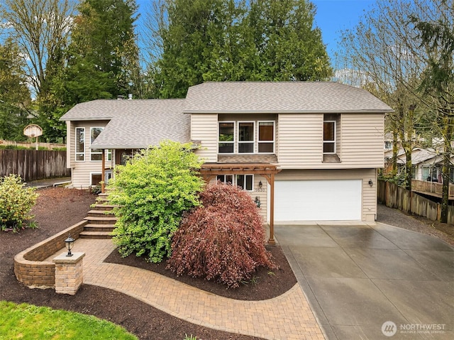 view of front facade featuring roof with shingles, a garage, fence, and driveway