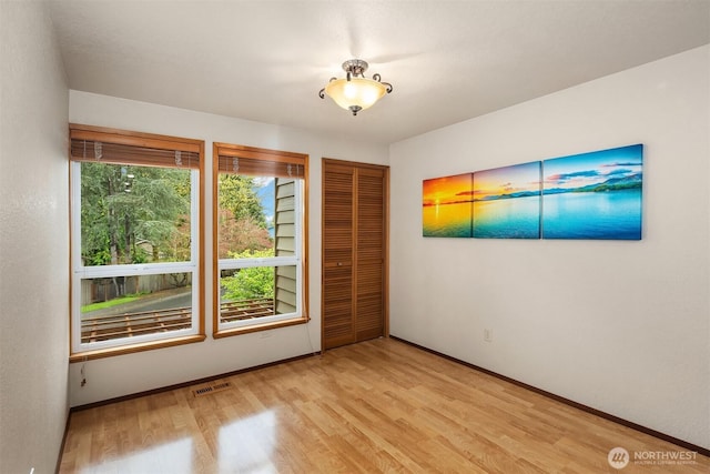 empty room with light wood-style floors, baseboards, and visible vents