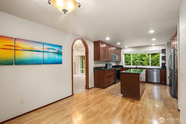 kitchen with light wood-style flooring, a center island, dark countertops, and stainless steel appliances