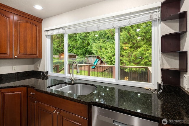 kitchen with stainless steel dishwasher, open shelves, recessed lighting, dark stone countertops, and a sink