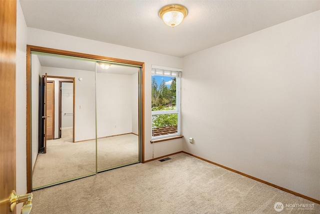 unfurnished bedroom with a closet, carpet, visible vents, and baseboards