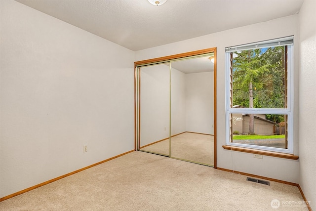 unfurnished bedroom with carpet, visible vents, a closet, and baseboards