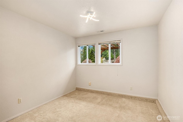 spare room with visible vents, baseboards, and light carpet