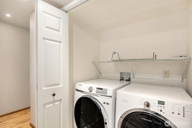 clothes washing area with baseboards, light wood finished floors, independent washer and dryer, and laundry area