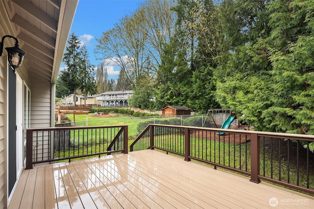 wooden deck featuring fence, a yard, and a playground