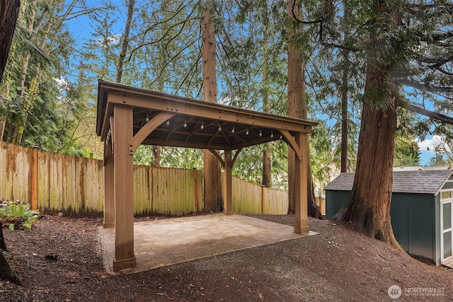 view of patio / terrace with an outbuilding, a storage unit, a fenced backyard, and a gazebo