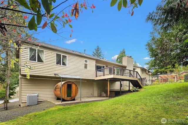 rear view of property with central AC unit, a wooden deck, fence, and a lawn