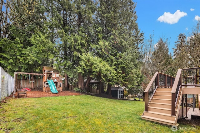 view of yard with an outbuilding, a fenced backyard, a playground, and a storage unit