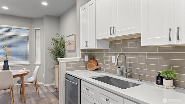 kitchen featuring a sink, dishwasher, light countertops, light wood-style flooring, and white cabinetry