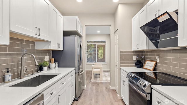 kitchen featuring light countertops, white cabinets, a sink, exhaust hood, and stainless steel appliances