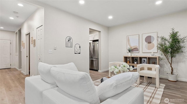 living area featuring recessed lighting, baseboards, and light wood-style flooring