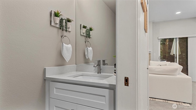 bathroom with recessed lighting, a textured wall, and vanity