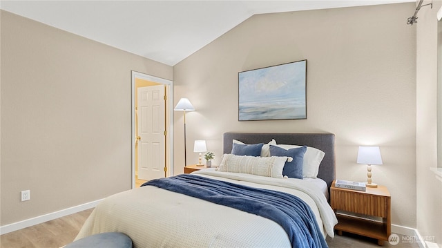 bedroom with baseboards, vaulted ceiling, and wood finished floors