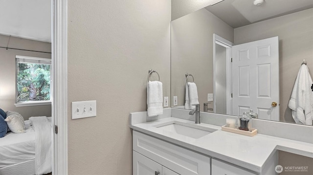 ensuite bathroom with a textured wall, ensuite bath, and vanity