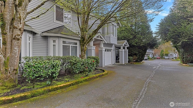 view of property exterior featuring an attached garage and driveway