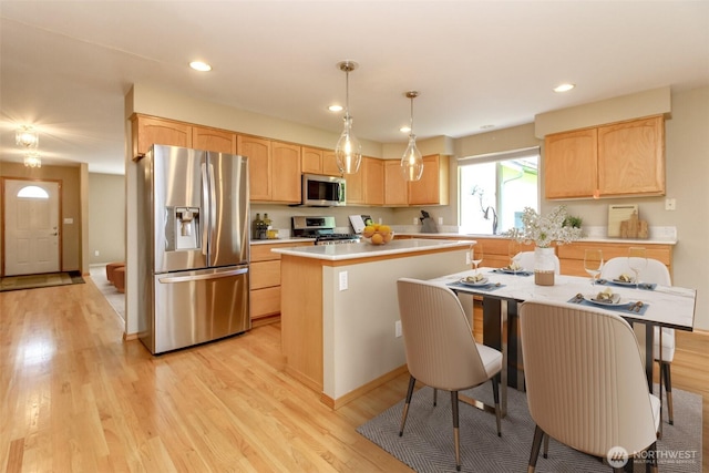 kitchen featuring a center island, light wood-style floors, light brown cabinetry, and stainless steel appliances