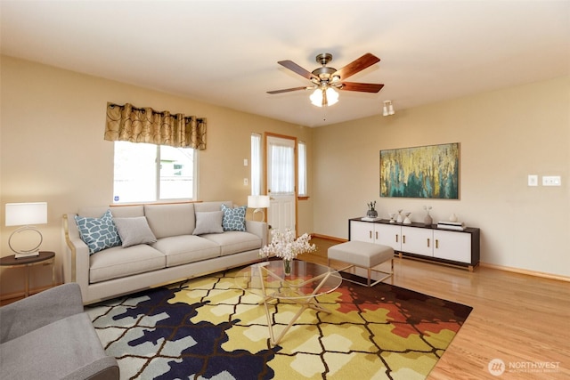 living room with baseboards, ceiling fan, and wood finished floors