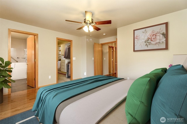 bedroom featuring ceiling fan, wood finished floors, ensuite bathroom, a spacious closet, and a closet