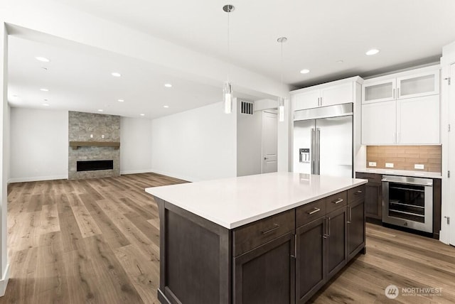 19512 81st Pl NE Unit 4, Kenmore, WA 98028 - kitchen with built in fridge, a fireplace, oven, white cabinetry, and light wood-style flooring