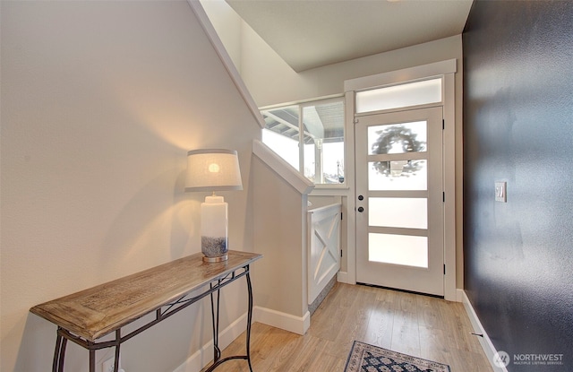 doorway to outside featuring baseboards and light wood-type flooring