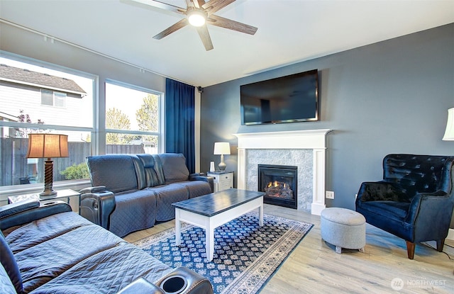 living area featuring a ceiling fan, a glass covered fireplace, wood finished floors, and lofted ceiling