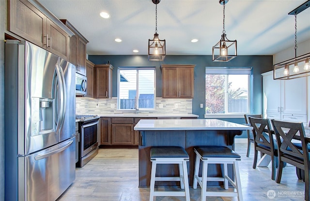 kitchen with light countertops, stainless steel appliances, a kitchen island, and a healthy amount of sunlight