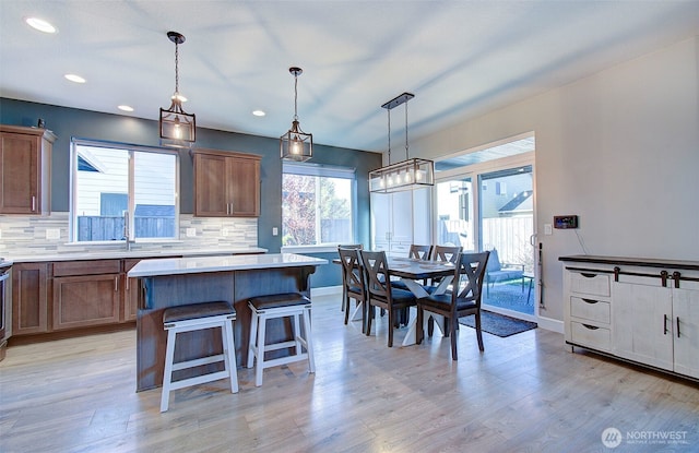 kitchen featuring a sink, a center island, decorative backsplash, and light countertops