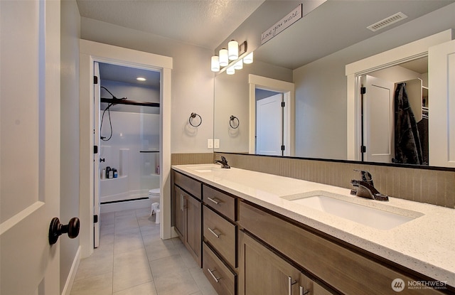 bathroom with toilet, visible vents, a sink, and a shower