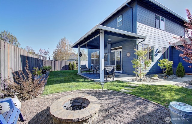 rear view of house featuring a lawn, a patio, a fire pit, and a fenced backyard