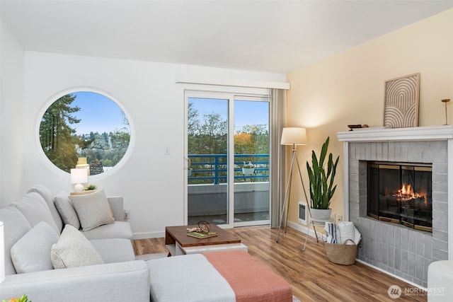 living area featuring a brick fireplace, baseboards, and wood finished floors