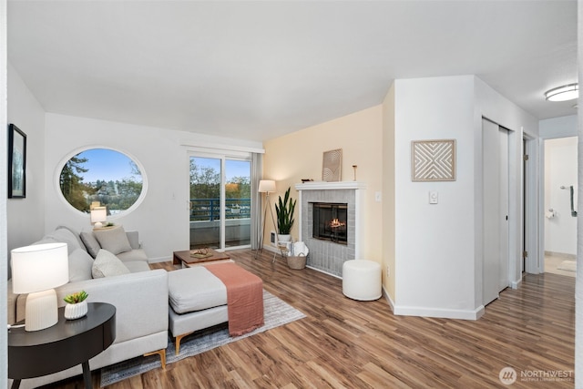 living area featuring wood finished floors, baseboards, and a brick fireplace