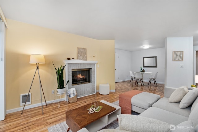 living area with wood finished floors, a fireplace, and baseboards