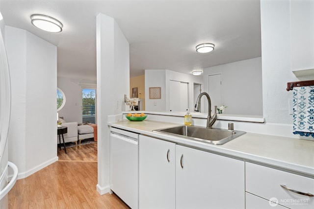 kitchen with a sink, light countertops, light wood finished floors, and dishwasher