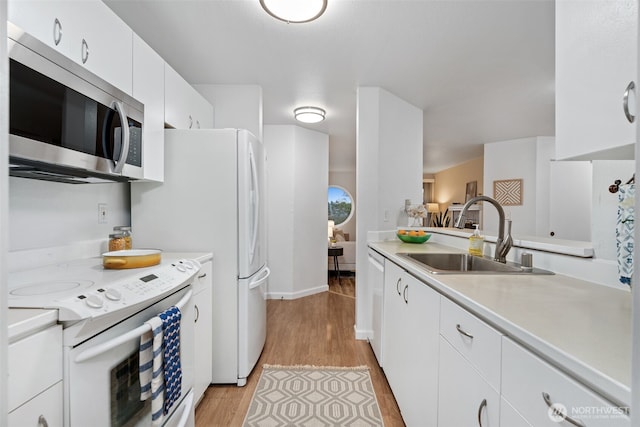 kitchen featuring light wood-style flooring, stainless steel microwave, light countertops, a sink, and white range with electric stovetop
