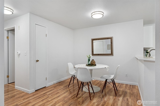 dining space with light wood finished floors and baseboards