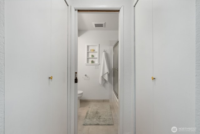 bathroom with toilet, built in shelves, visible vents, and bath / shower combo with glass door
