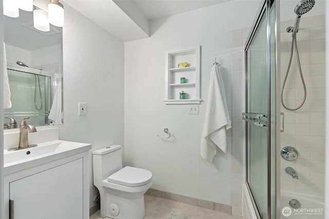 bathroom with shower / bath combination with glass door, vanity, baseboards, and toilet